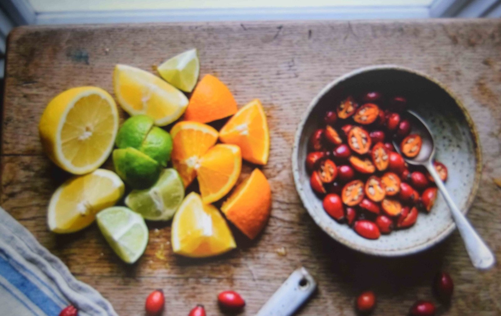 Chopped citrus with peel intact beside a bowl of halved rosehips