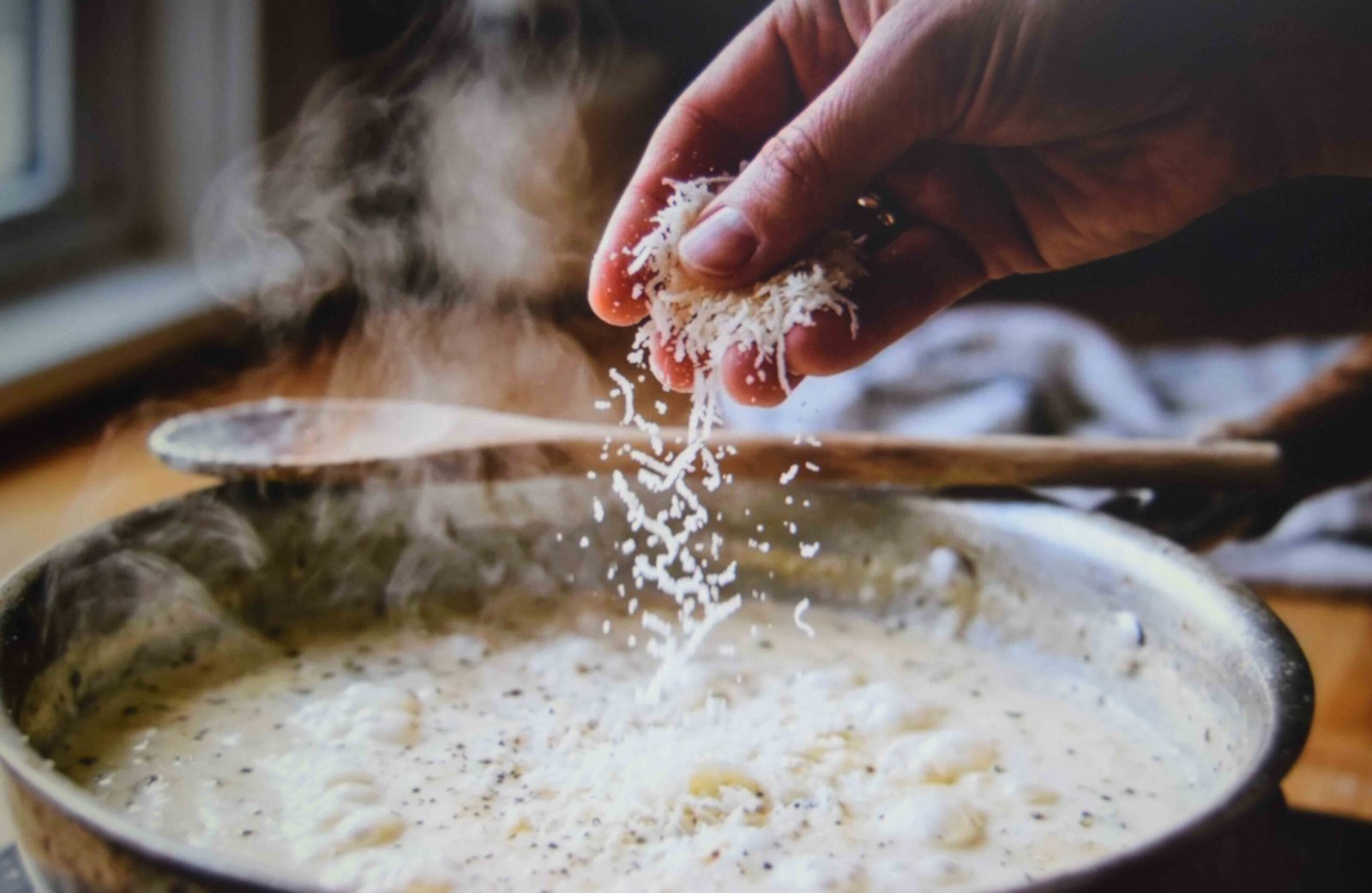 Parmesan added gradually into the simmering cream and stock sauce
