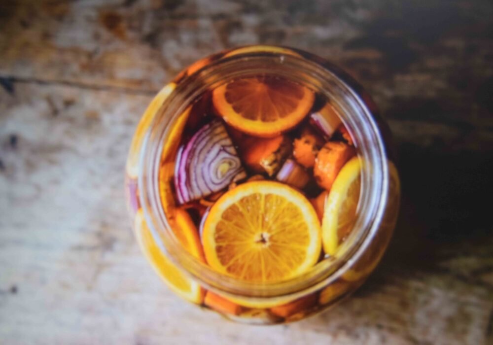 A packed half gallon jar showing a fire cider recipe steeping in apple cider vinegar