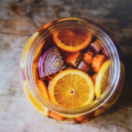 A packed half gallon jar showing a fire cider recipe steeping in apple cider vinegar
