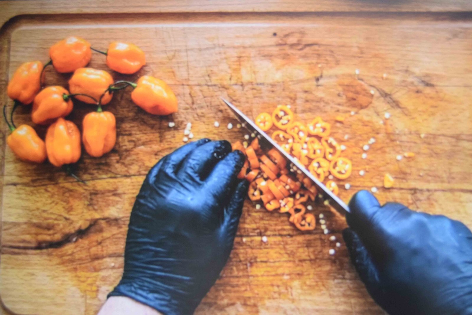 Habanero peppers chopped with gloves on a separate board