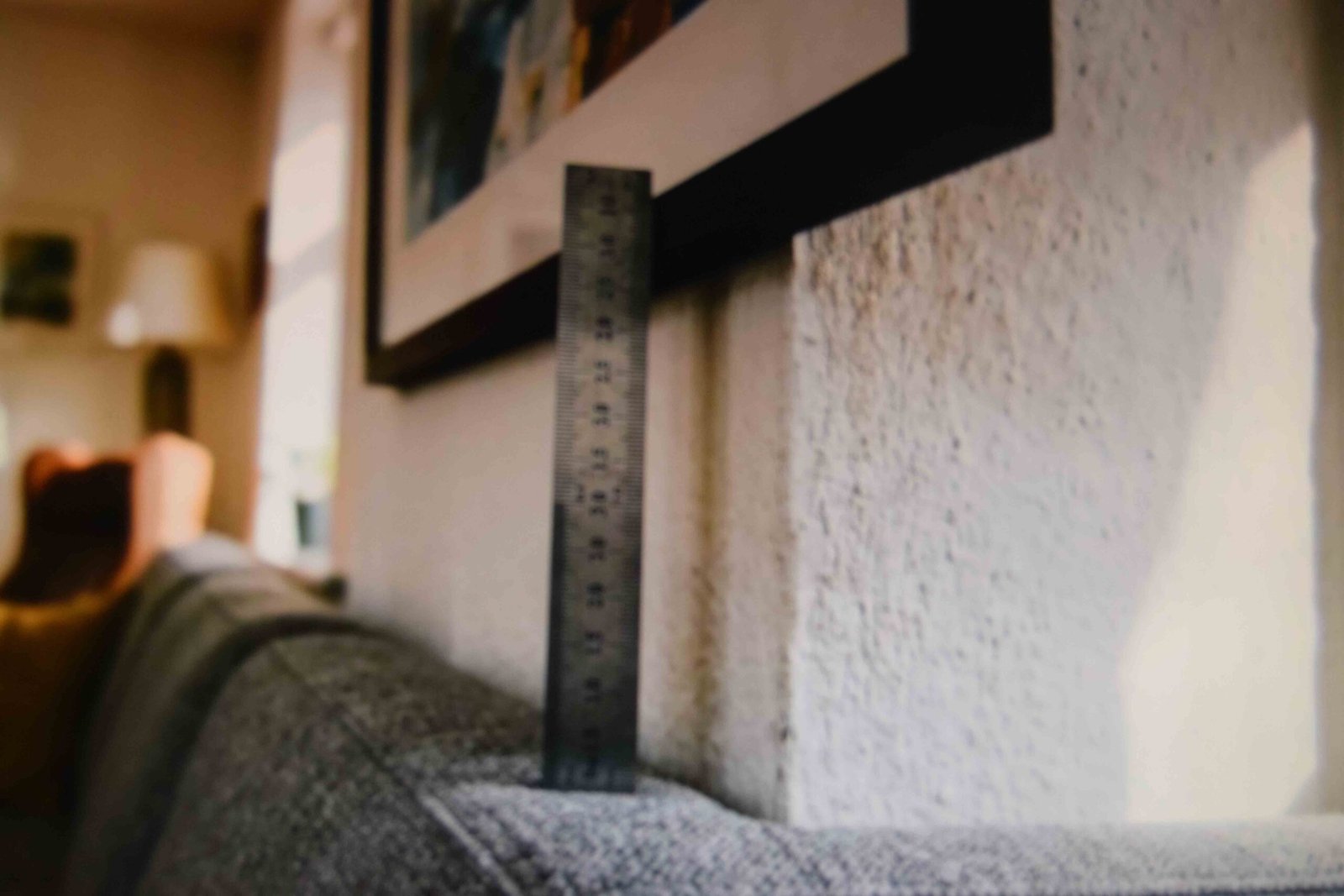 A ruler measuring the small gap between a sofa back and the frame above it