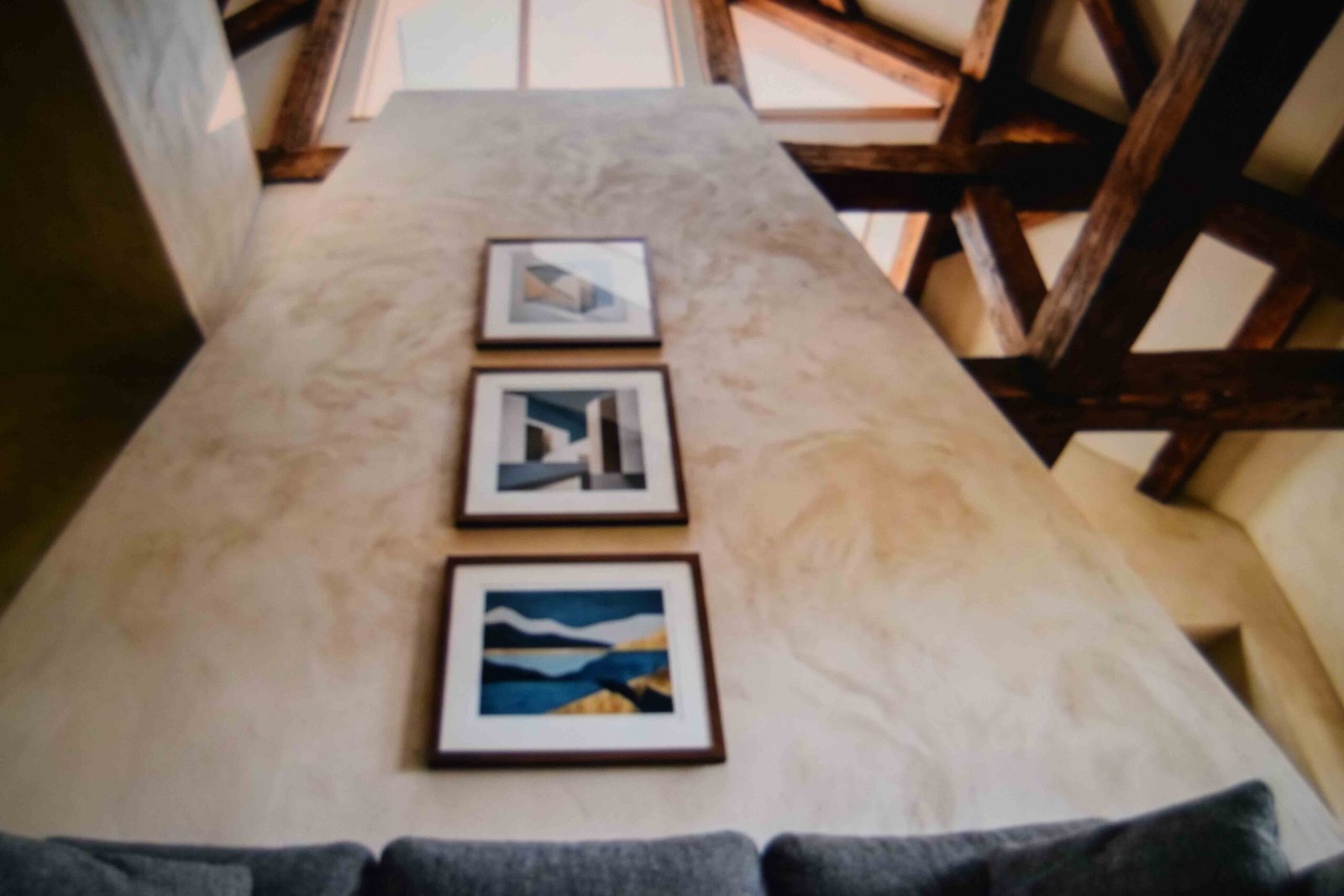 Three framed pieces stacked in a column up a vaulted living room wall