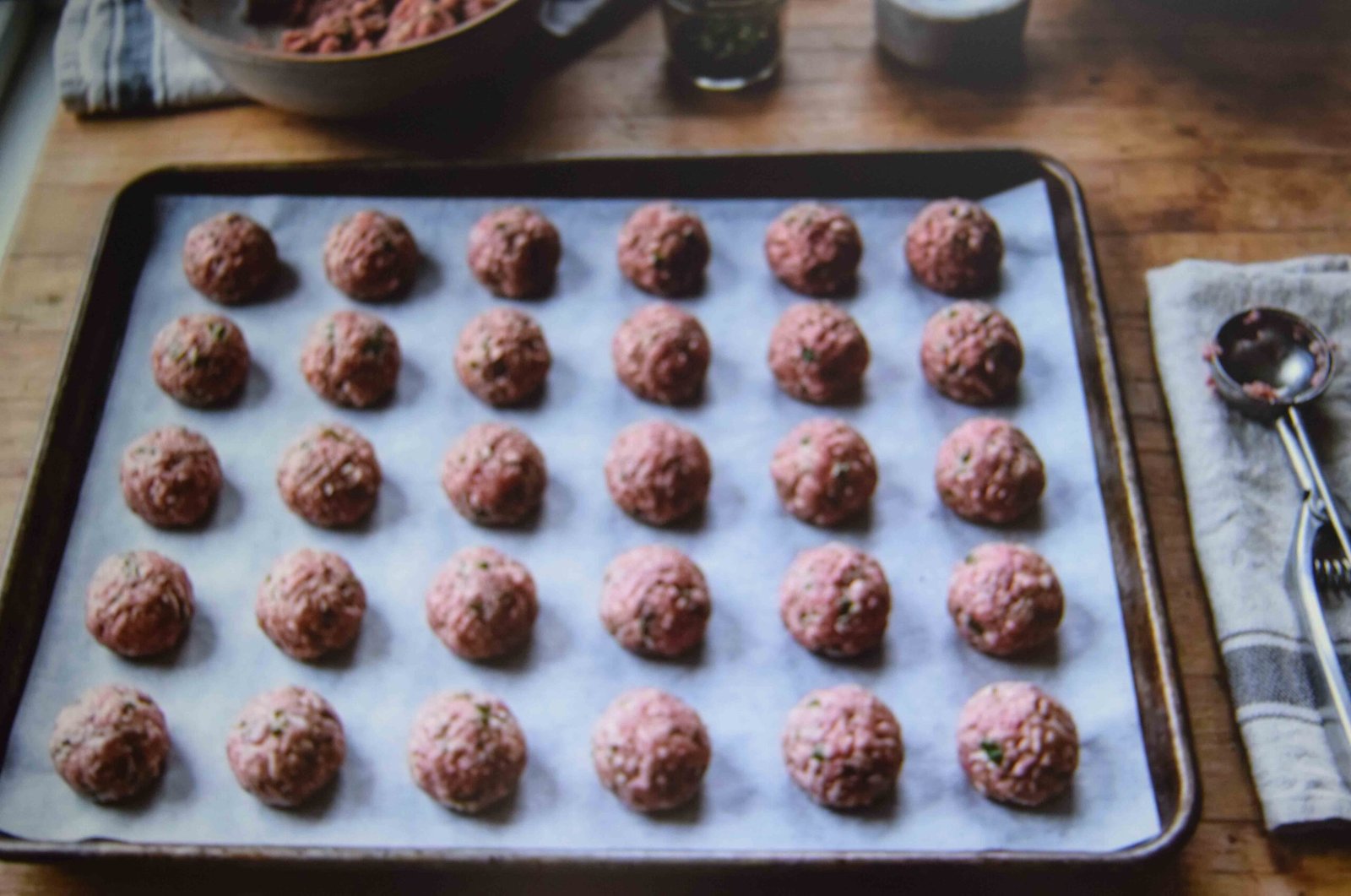 Evenly sized raw chicken meatballs rolled and lined up on a tray