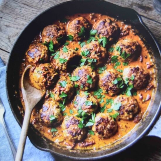 A skillet of marry me meatballs in sun dried tomato cream sauce finished with parsley