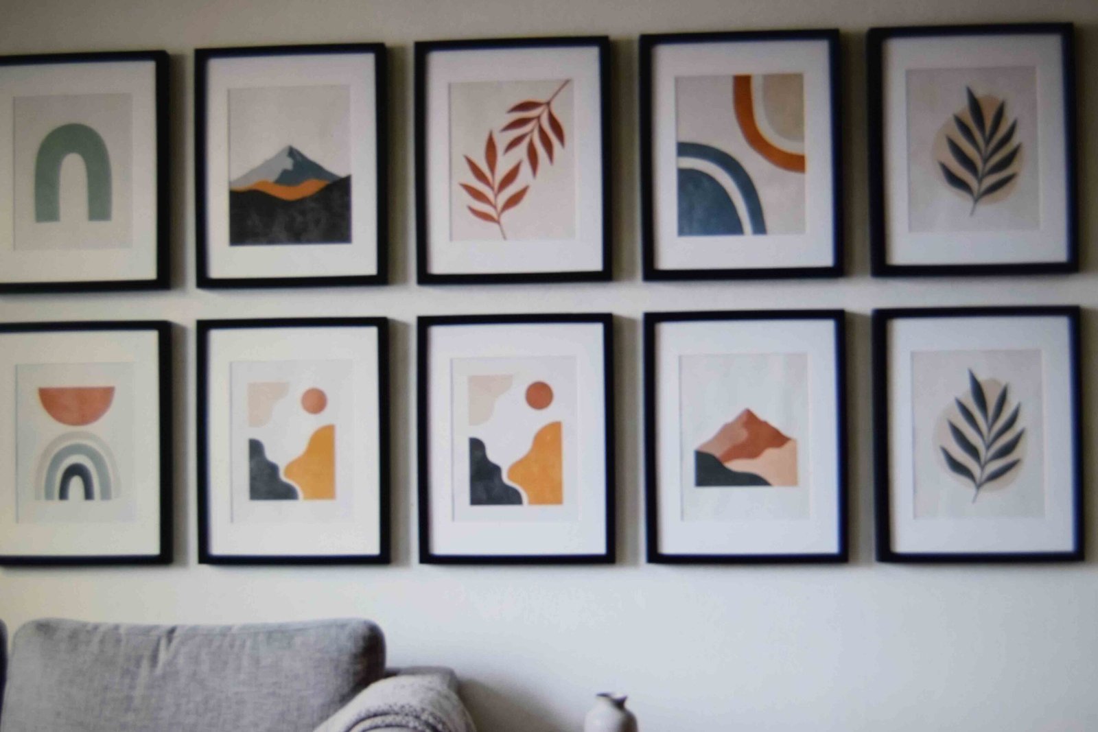 Nine identical frames hung in an even grid above a sofa arm