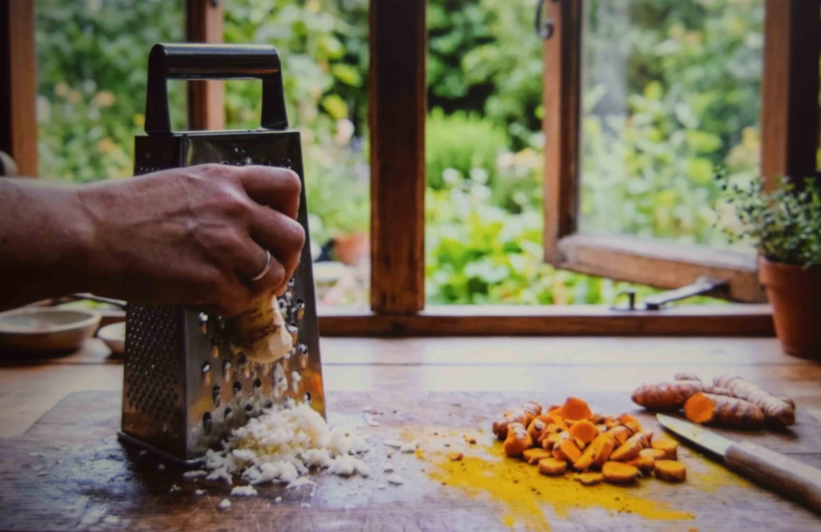Horseradish being grated beside turmeric staining a wooden board
